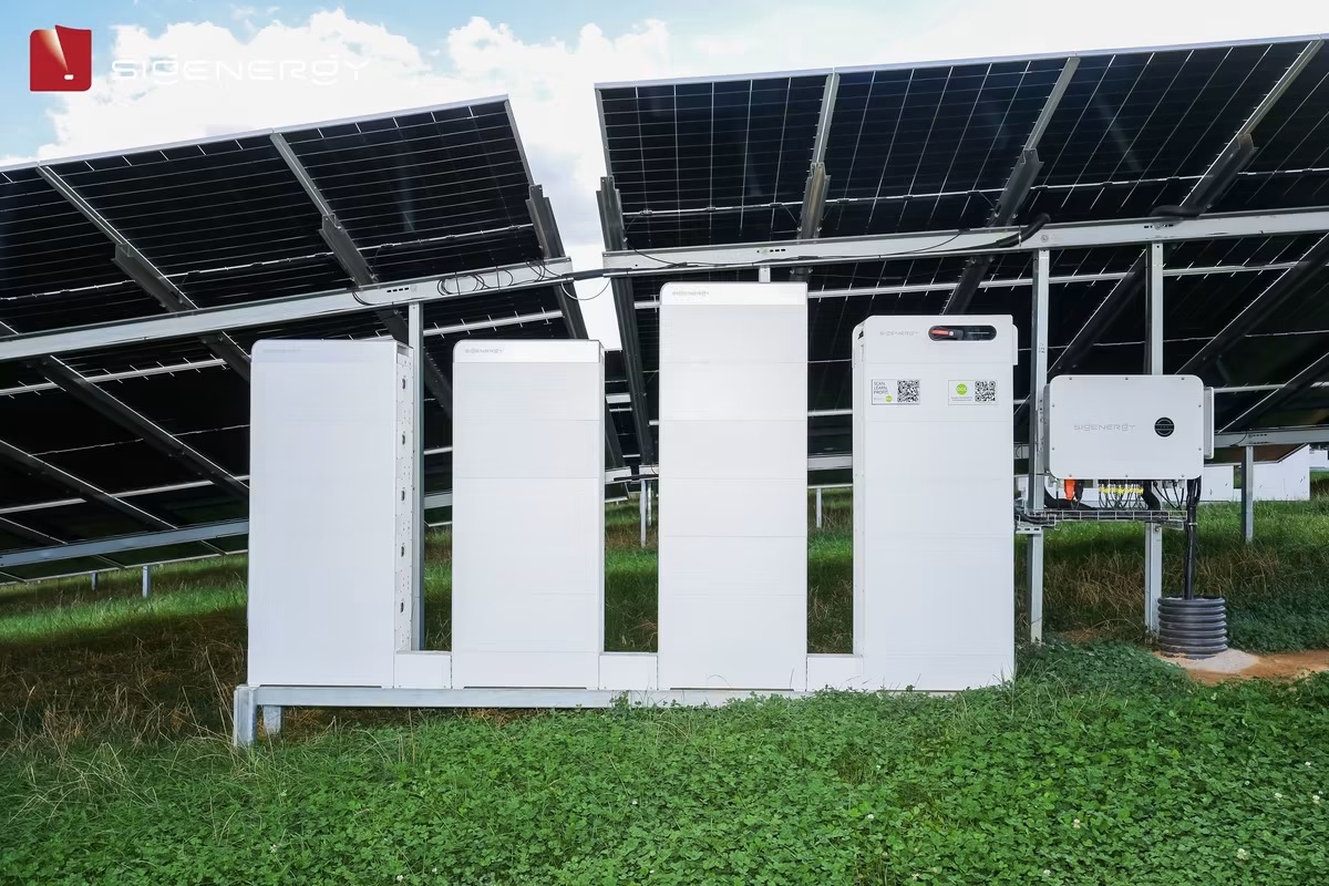 SigenStack battery towers and inverter beneath a ground-mounted solar array on grass