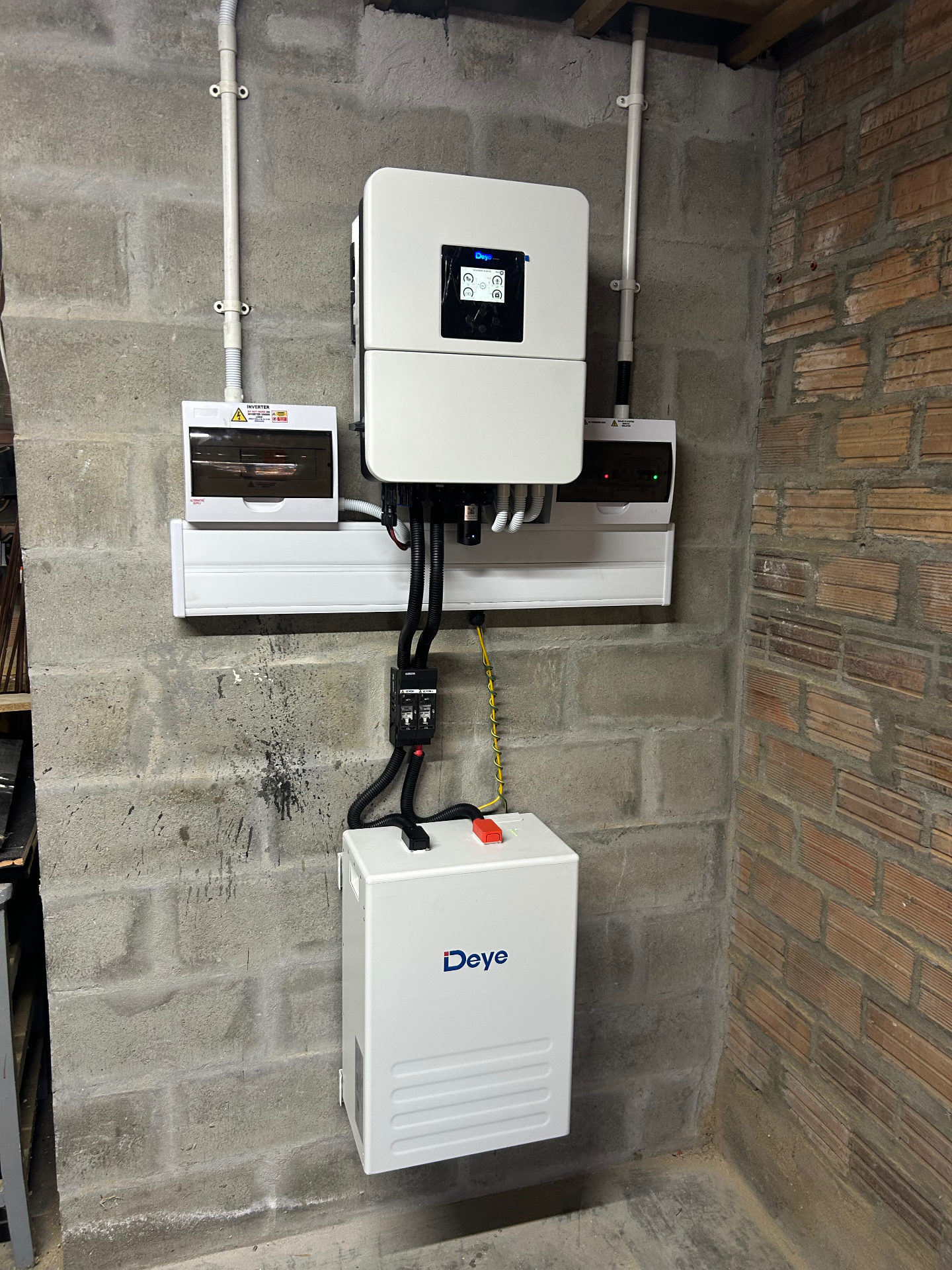 Deye hybrid inverter and wall-mounted Deye battery installed in a garage, with new distribution boards